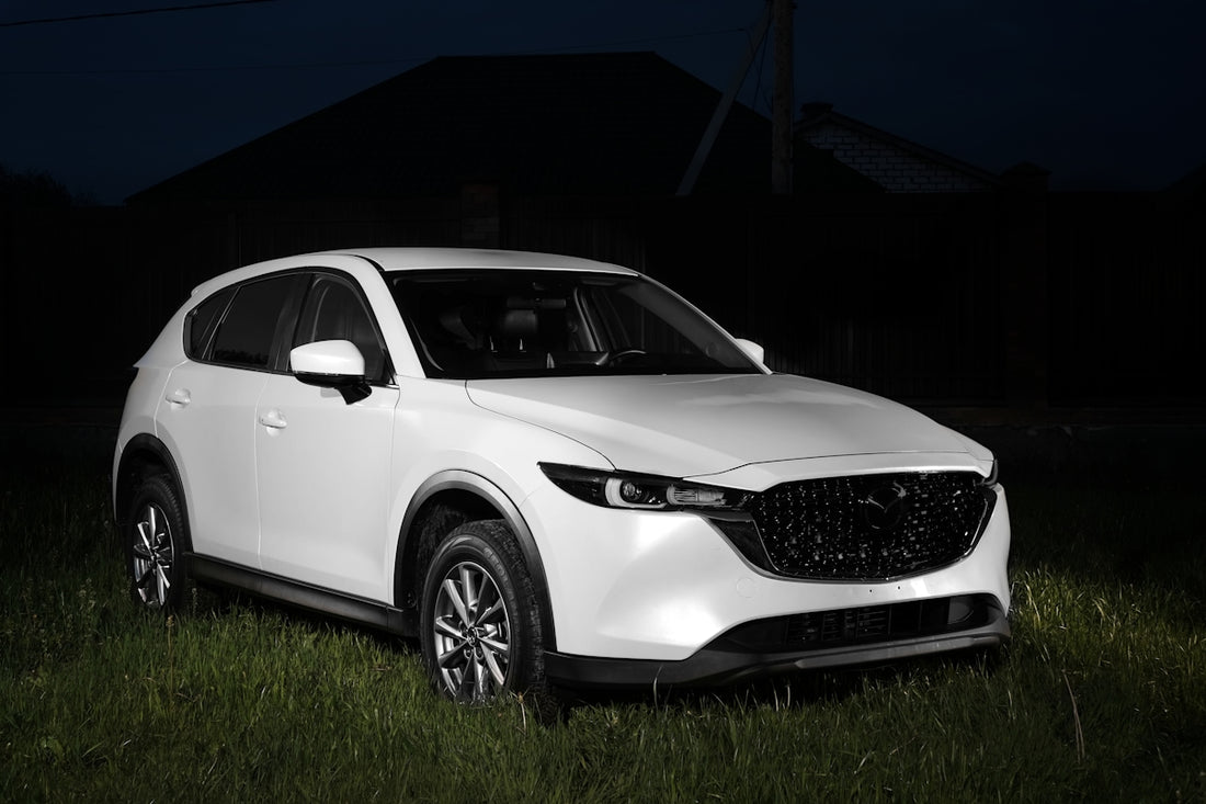 a white mazda cx - 5 parked in a field at night