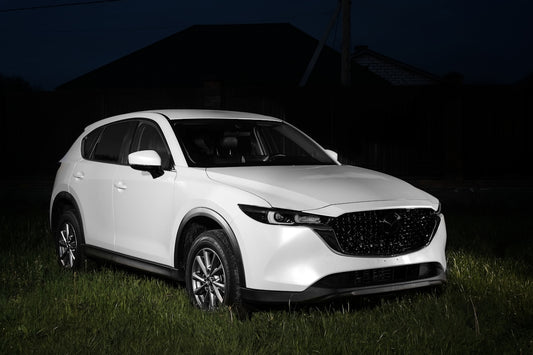 a white mazda cx - 5 parked in a field at night