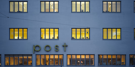 Building with illuminated windows and post sign at dusk