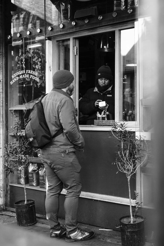 Man ordering coffee from a street vendor