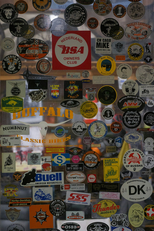 Collection of vintage motorcycle club stickers on a surface.