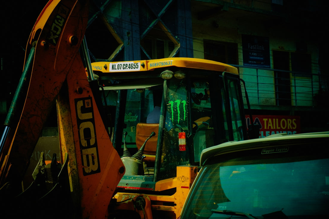 Yellow jcb backhoe loader with monster logo at night.