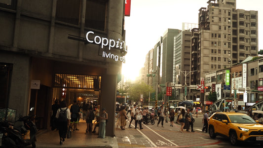 Crowded city street with people crossing and buildings at sunset.