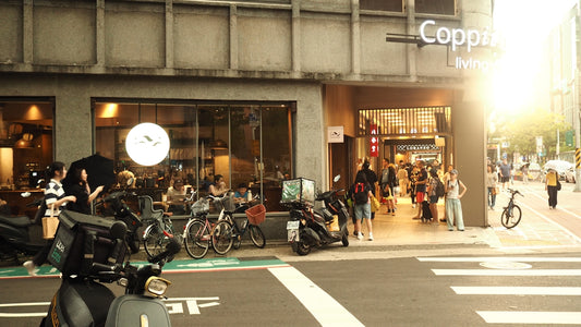 Busy city street with people, motorcycles, and buildings at sunset.