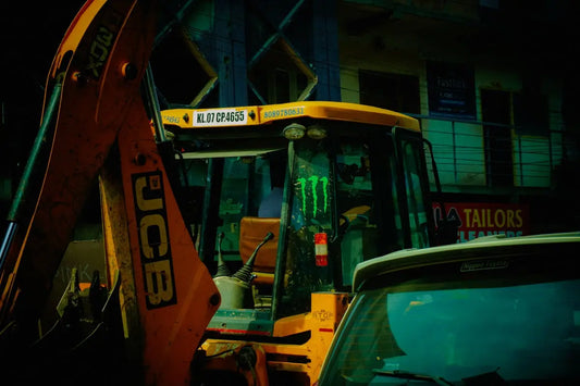 Yellow jcb backhoe loader with monster logo at night.