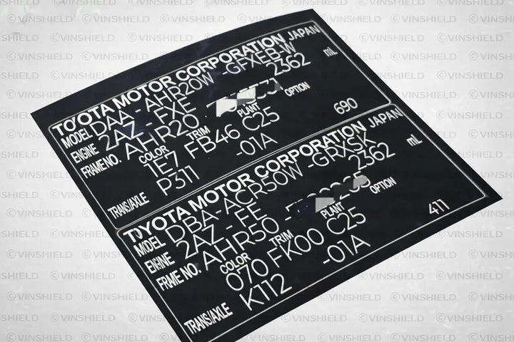 Black plastic vehicle identification plate with white printed text detailing toyota model and engine specifications.