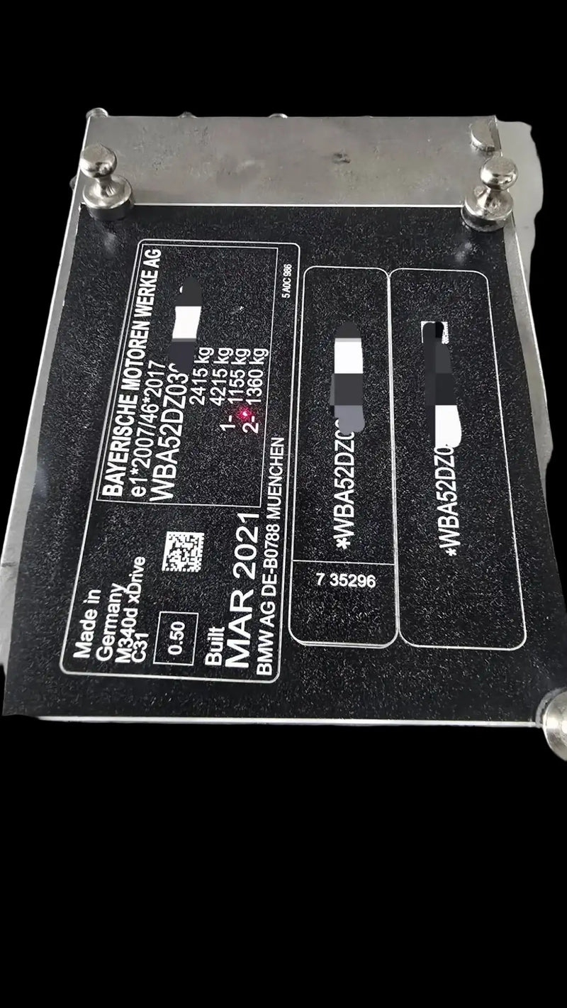 Black rectangular engine plate with silver metallic corners and white printed text, featuring bmw branding and technical specifications.