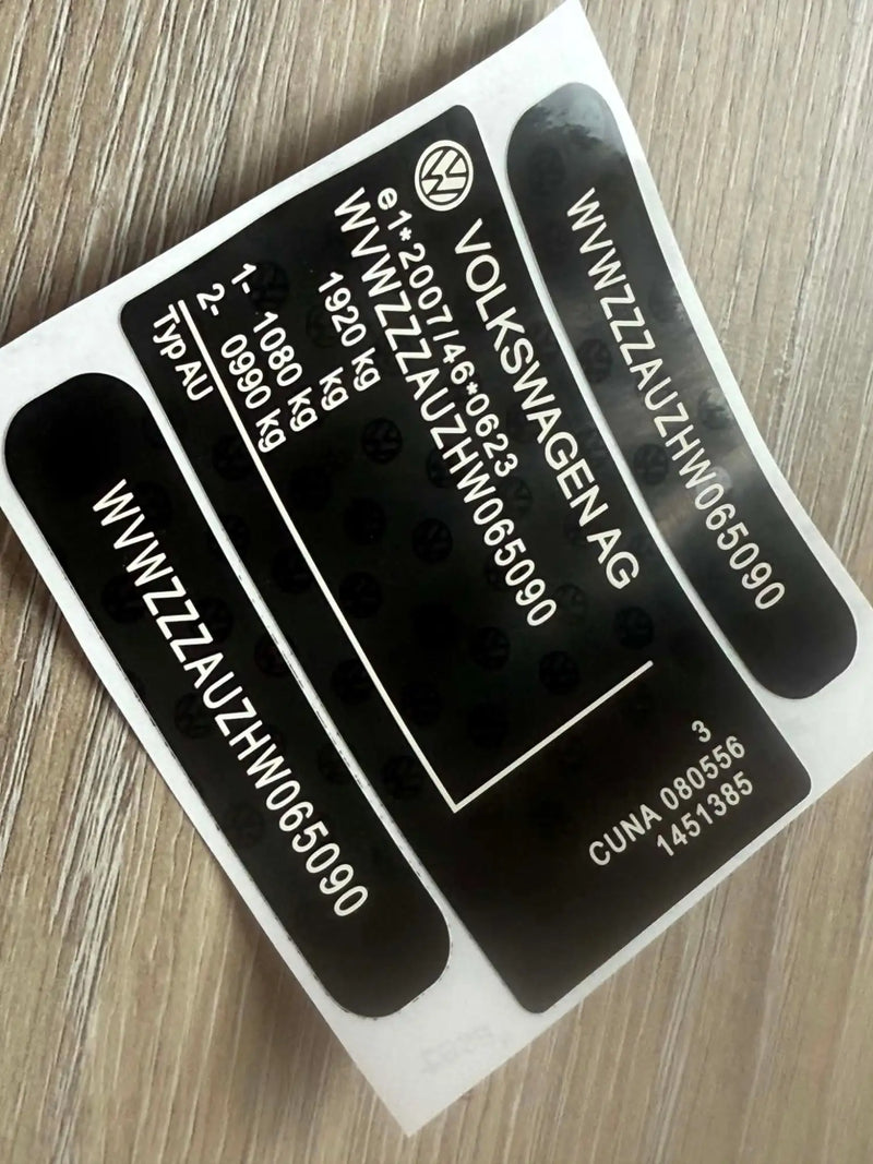 Black volkswagen vehicle identification label with white text and a circular logo.