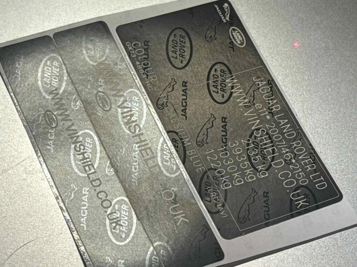 Dark gray metallic vehicle identification plates with embossed jaguar land rover logos and vin information.