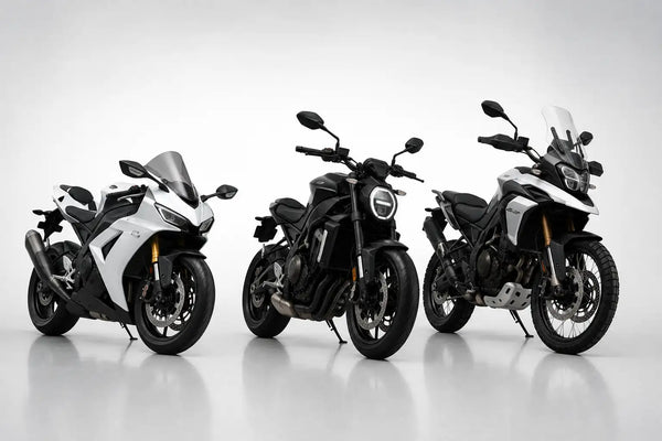Three motorcycles, including a white and black sport bike, a matte black cruiser-style model with a round headlight, and another adventure touring motorcycle in black and white.